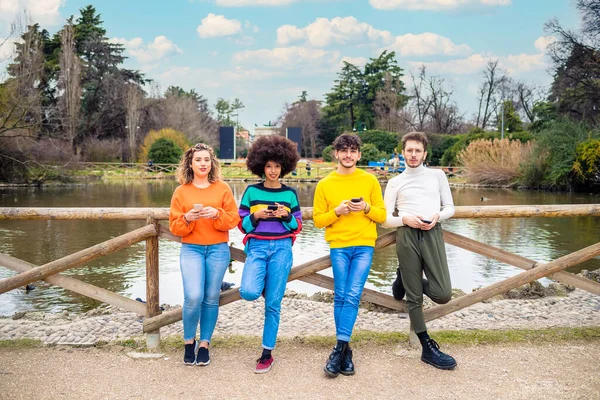 Grupo Amigos Multiétnicos Millennials Usando Teléfonos Móviles Abrazándose Mirando Cámara — Foto de Stock