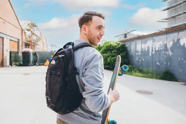 Mladý Kavkazský Sportovní Bruslař Muž Chůze Venku Držení Skateboard Úsměvem — Stock fotografie