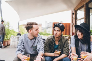 Dört etnik gruptan oluşan bir grup açık hava kulübünde oturup sohbet ediyor ve birlikte iyi vakit geçiriyorlar.