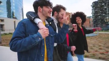 Bir grup arkadaş turist birlikte yürüyorlar şehir merkezinde kucaklaşıyorlar geziyorlar eğleniyorlar, gülüyorlar ve tatilden keyif alıyorlar dans ediyorlar ve şarkı söylüyorlar.