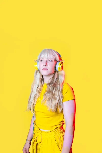 演播室拍摄年轻的金发白人女性 背景是黄色的 戴着耳机欣赏着好听的音乐 — 图库照片