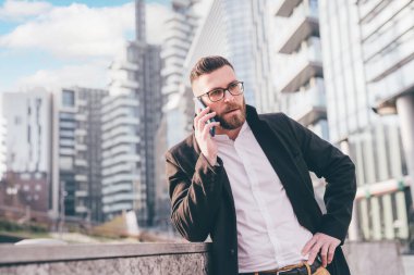 Kafkas sakallı genç iş adamı akıllı telefonlardan hoşlanır. Endişeli ve endişeli bir konuşma yapar. 