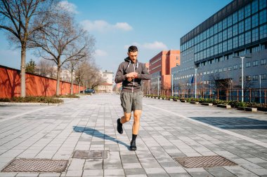 Genç beyaz bir adam şehirde maraton antrenmanı yapmak için dışarıda koşuyor.