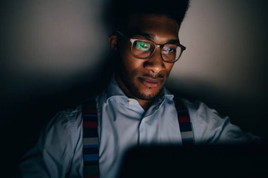 Genç yakışıklı adam bilgisayar kumandası kullanarak geceleri uyanıyor.