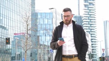 Slow motion young caucasian bearded business man outdoor trading and financing with smartphone handhold with confidence and attitude