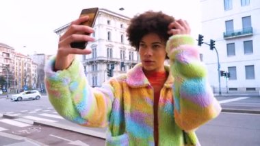 Yavaş çekim genç, güzel, melez, arka plan kızı popüler eğilimleri takiben sosyal medyada akıllı telefon paylaşımı yaparak selfie çekiyor.