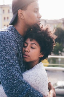 Genç siyah romantik çift açık havada birbirlerine sarılıyorlar gözleri kapalı korunuyor ve seviliyorlar.