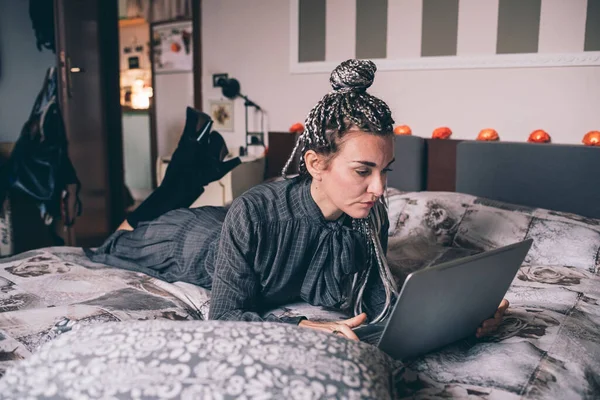 코카서스 여자는 컴퓨터를 사용하여 집안에 침대를 마련하고 — 스톡 사진