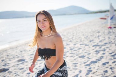 Genç İspanyol kadın plajda mayo giyiyor.