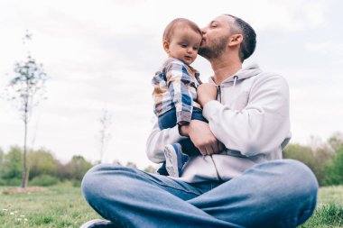 Baba oğluna sarılıp parkta öpüşüyor.