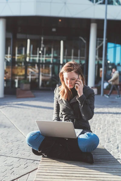 Mujer Joven Sentada Aire Libre Usando Portátil Hablando Teléfono Inteligente — Foto de Stock