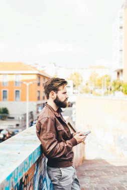 Genç yakışıklı sakallı adam akıllı telefon kullanarak video izliyor.