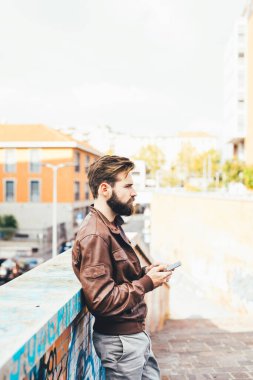 young handsome bearded man using smartphone watching streaming video clipart