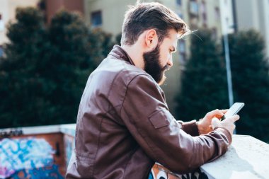 Akıllı telefon blogu kullanan genç ve yakışıklı sakallı adam.