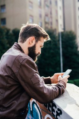 Genç sakallı adam internette akıllı telefon ticareti yapıyor.