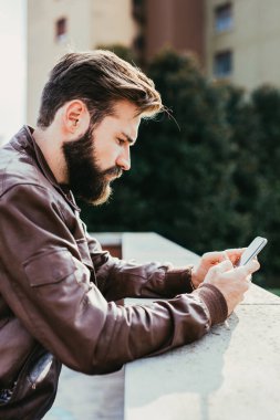 Genç sakallı adam akıllı telefon kumandası kullanıyor.