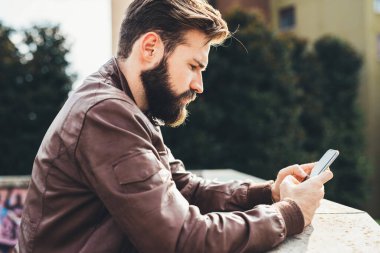 Genç yakışıklı sakallı adam akıllı telefon kullanıyor sosyal medya paylaşımı