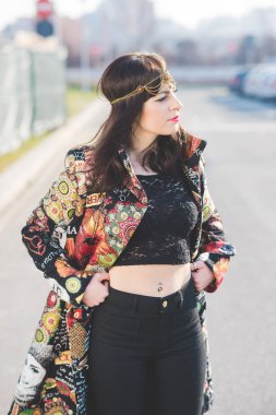 Genç ve güzel bir kadın şehrin dışında poz veriyor. Kendine güveniyor.