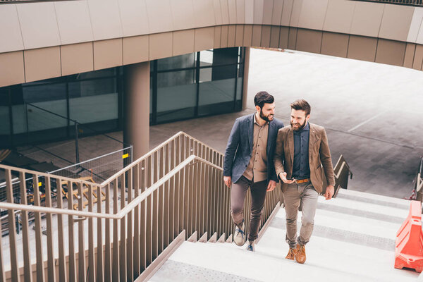 Two contemporary businessman walking upstairs talking