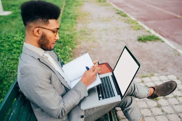 Young black professional businessman remote working using computer writing note