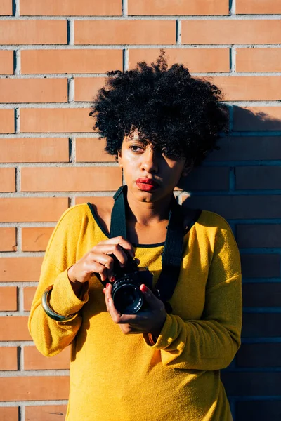 年轻的非洲卷曲棕色头发的女人拿着相机拍照 — 图库照片