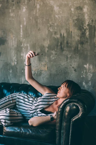 Wanita Muda Berbaring Sofa Dalam Ruangan Menggunakan Smartphone Mengambil Selfie — Stok Foto