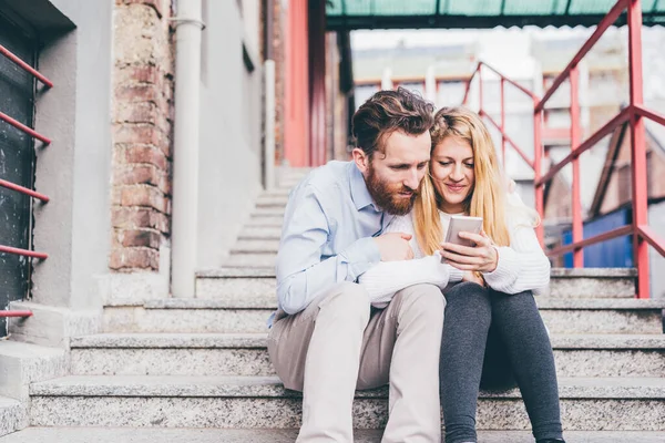 スマートフォンの笑顔のショッピングやオンライン予約を一緒に屋外で若いカップル — ストック写真