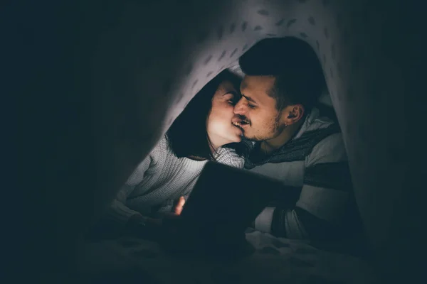 Pasangan Muda Dalam Rumah Berbaring Bawah Seprai Menggunakan Ciuman Bingewatching — Stok Foto