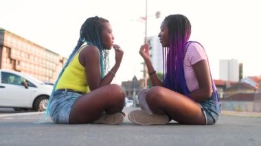 İki zenci kız kardeş dışarıda sohbet ediyor ve birlikte güzel vakit geçiriyorlar.