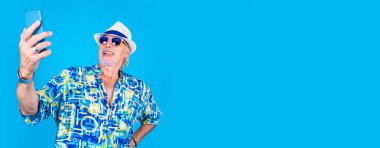 Üst düzey beyaz adam akıllı telefon kullanıyor. Selfie çekiyor ya da video sohbeti yapıyor. Reklam arkaplanda izole edilmiş.