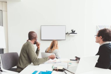 Üç iş adamı konferans yapıyor ve boş akıllı ekranla etkileşimde bulunuyor 