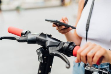 Tanımlanamayan kadın akıllı telefon kullanıyor. QR kodunu tarıyor ve scooter 'ı açıyor.
