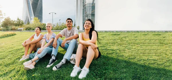 Grupo Jóvenes Amigos Multiétnicos Sentados Aire Libre Contemplando Sonriendo Positivo —  Fotos de Stock