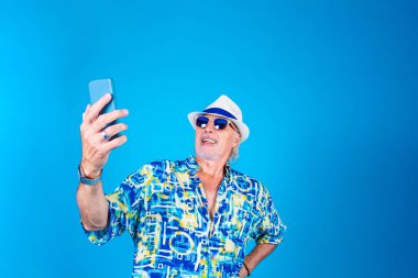 Beyaz adam tatilde. Akıllı telefon kullanıyor. Selfie çekiyor ya da görüntülü sohbet yapıyor. 