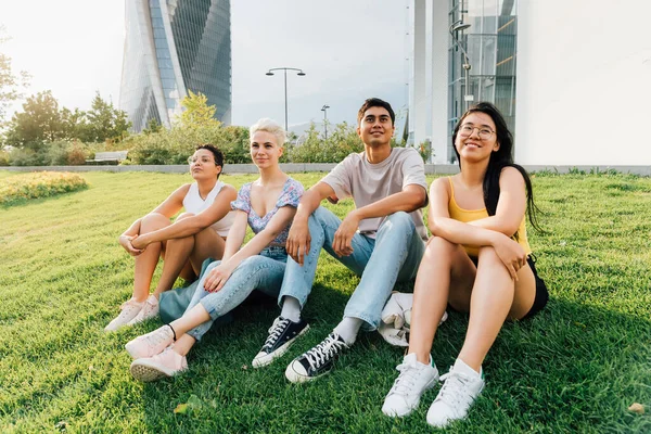 Grupo Jóvenes Amigos Multiétnicos Sentados Aire Libre Contemplando Sonrientes Positivas —  Fotos de Stock