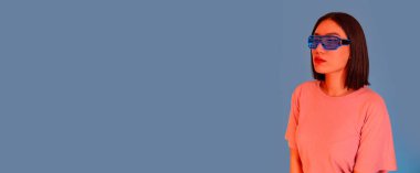 Kulaklık takan genç Asyalı kadın ve fütüristik gözlük takan yalnız kesilmiş reklam alanı arka planı