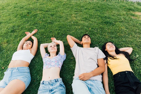 若い多民族の友人のグループ屋外の横に草の笑顔自由とリラックス感 広告コピースペースバナー — ストック写真