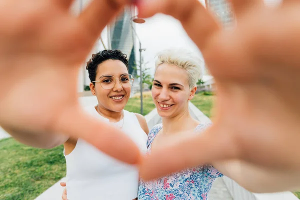 年轻的同性恋多种族女同性恋夫妇在户外做心形 双手笑容满面 — 图库照片