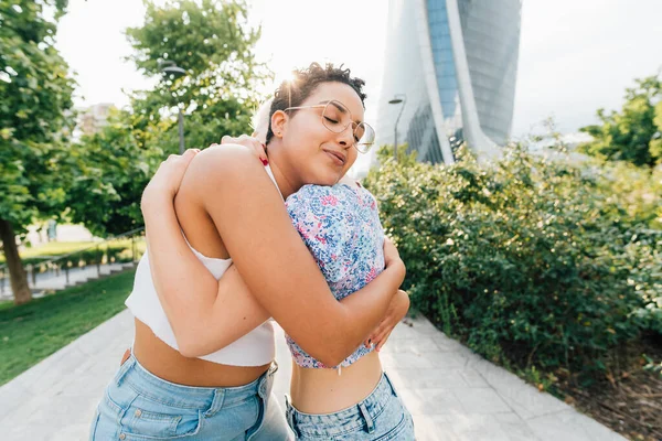 两只年轻的多民族女性同性恋伴侣拥抱在户外 开心地微笑着 表达爱意 — 图库照片