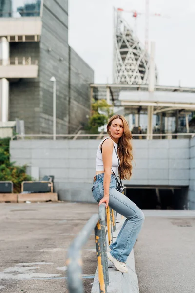 Genç beyaz kadın turist dışarıda poz veriyor. Geleceğe inanmayı düşünüyor.