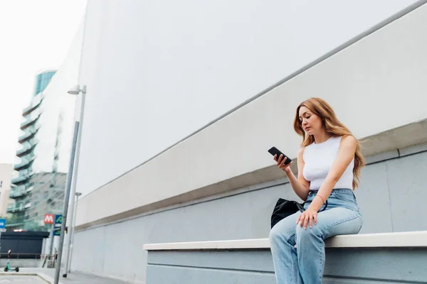 年轻的高加索女人坐在室外使用智能手机上网购物和交易 广告版权空间 — 图库照片