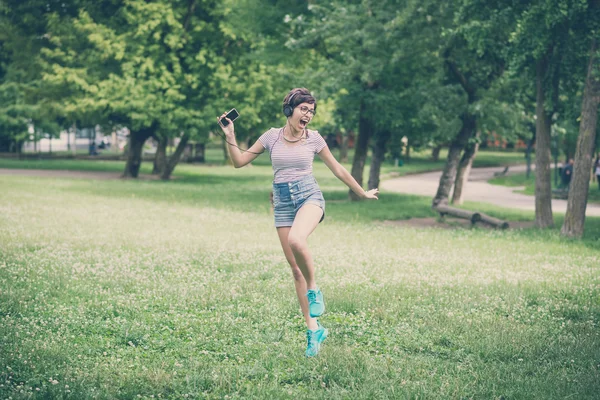 Young hipster woman listening to music jumping — Stock Photo, Image