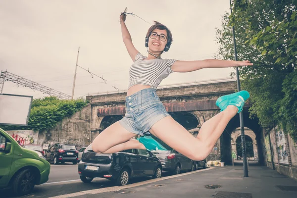 Jonge hipster vrouw luisteren naar muziek springen — Stockfoto