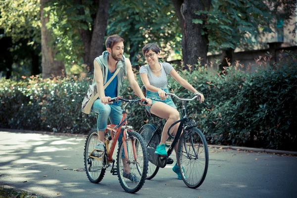 Couple of friends young  man and woman riding bike — Stock Photo, Image