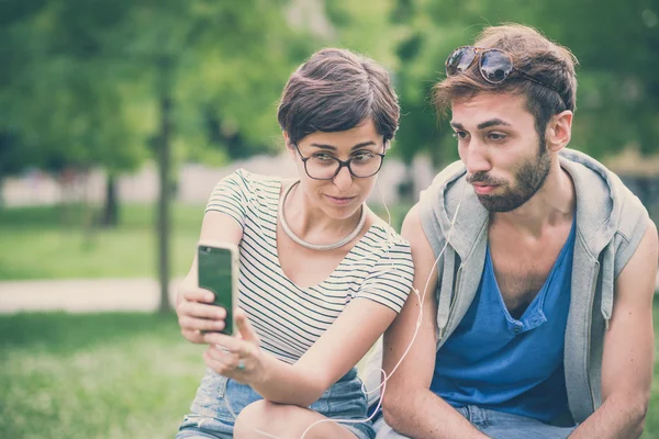 Casal de amigos jovem e mulher usando smartphone — Fotografia de Stock