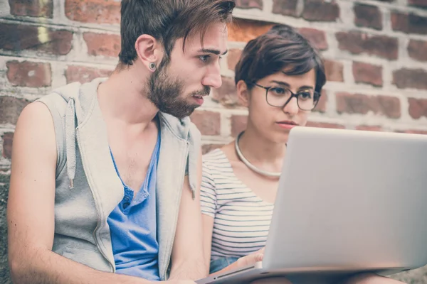 Par vänner ung man och kvinna med laptop — Stockfoto
