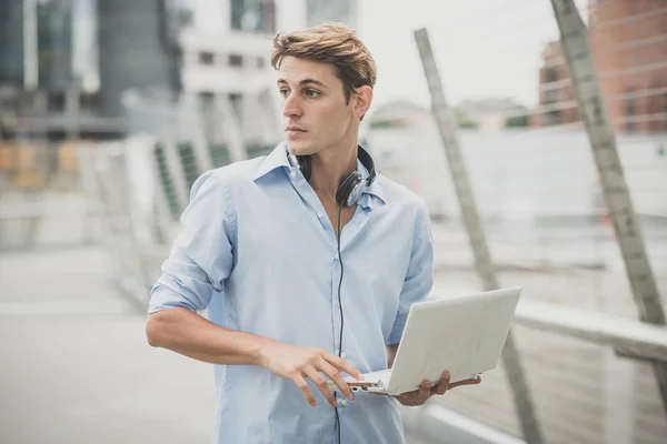 Joven modelo hansome hombre rubio con portátil y auriculares —  Fotos de Stock