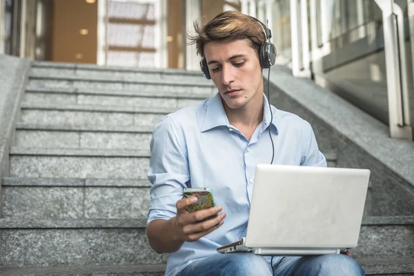 Joven modelo hansome rubia hombre auriculares y portátil —  Fotos de Stock