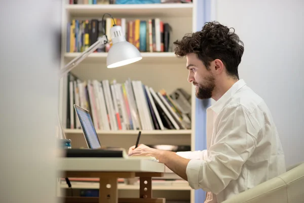 Guapo hipster moderno hombre trabajando en casa usando el ordenador portátil —  Fotos de Stock