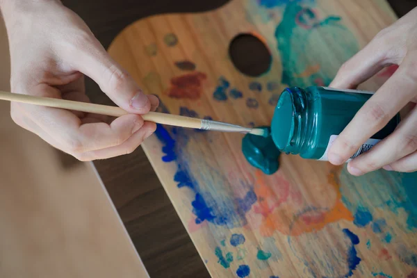Close up hands using paintbrush and colours — Stock Photo, Image